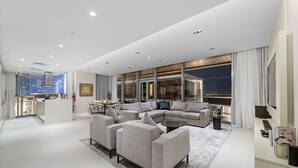A modern living room with a sectional sofa, a dining area, and a view of the cityscape.