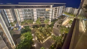 A modern hotel with multiple floors, a courtyard with palm trees, and a well-lit exterior.