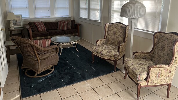 Una sala de estar con un sofá, dos sillones, una mesa de centro y una alfombra.