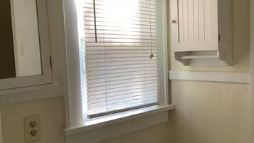 Un baño con inodoro, lavamanos y ventana con persianas.