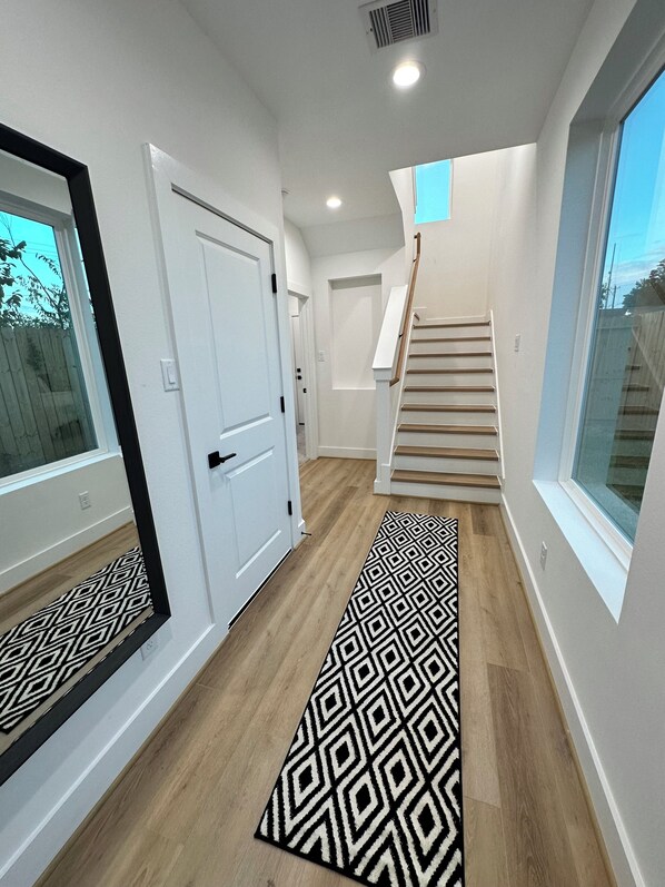 A hallway with a patterned rug, a white door, and a staircase leading to another floor.
