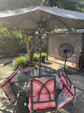 Un patio con mesa y sillas, un ventilador y una mosquitera.