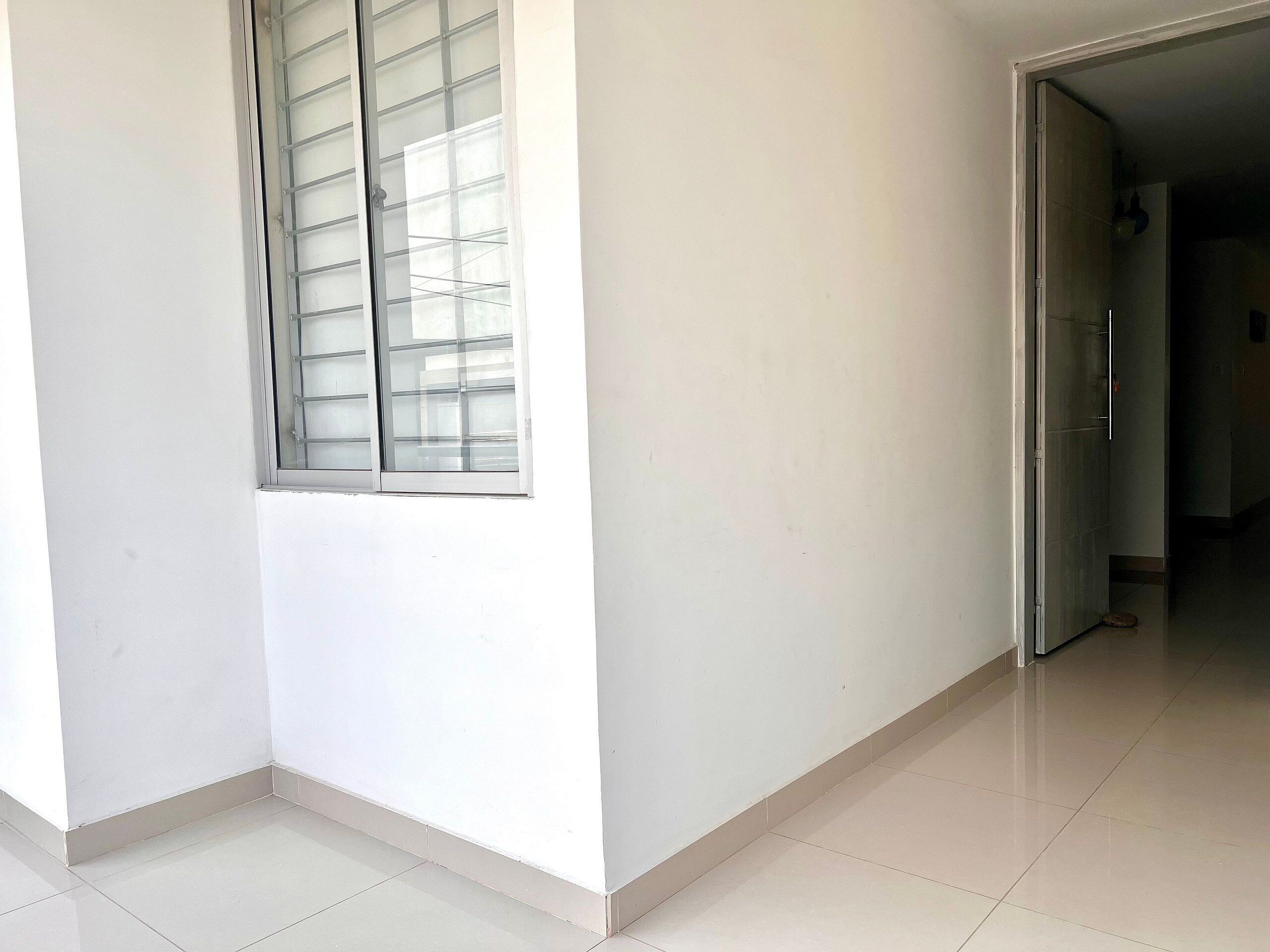 A corner of a room with a window, a door, and a tiled floor.