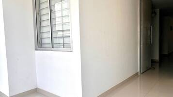 A corner of a room with a window, a door, and a tiled floor.