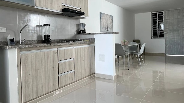 Una cocina moderna con armarios de madera, una isla integrada y un comedor con sillas.