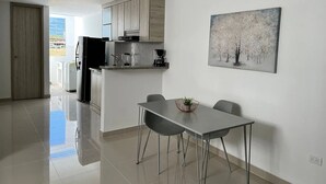 Una cocina moderna con comedor, un cuadro en la pared y vistas a través de una puerta abierta.