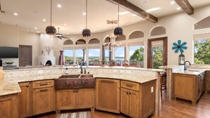 A spacious kitchen with wooden cabinets, a large island, and pendant lighting. - Riviera Paradise | Lake Access (Canyon Lake)
