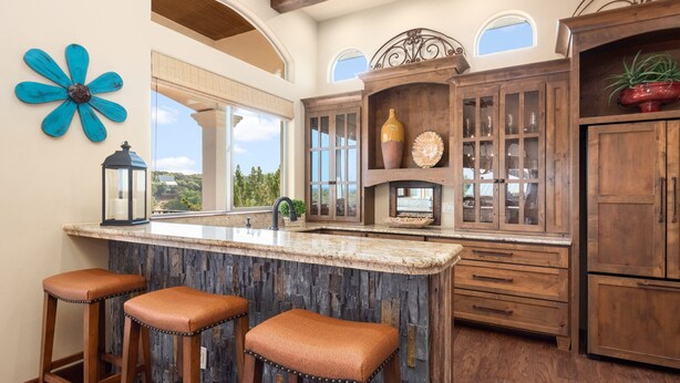 A kitchen with a large island, wooden cabinets, and a blue flower decoration. - Riviera Paradise | Lake Access (Canyon Lake)