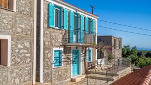 A stone building with a balcony, a door, and a window with shutters. - Villa 'Milia's House' with Sea View, Wi-Fi and Air Conditioning (Ithaca)