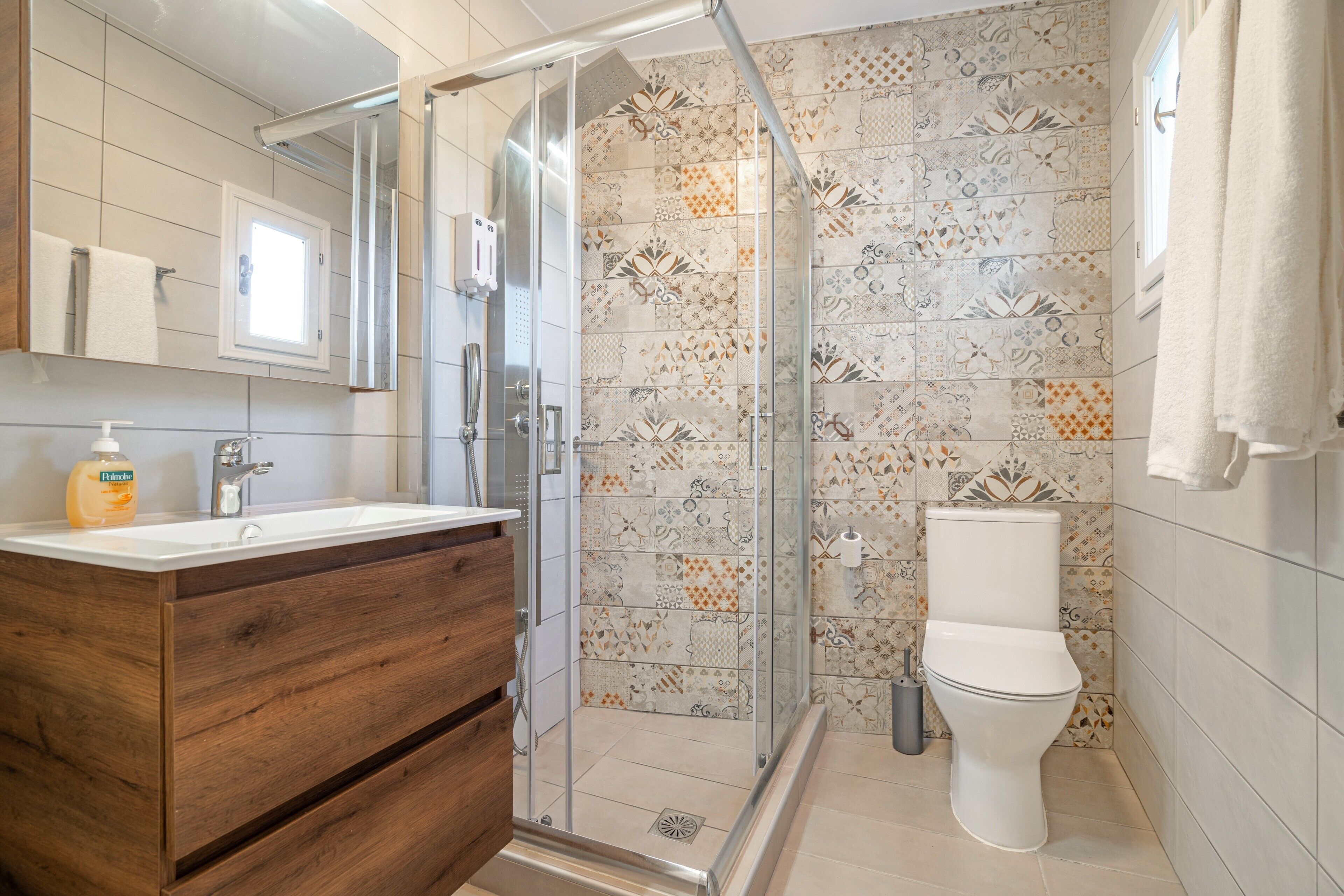 Une salle de bain avec douche, toilettes et meuble-lavabo en bois.