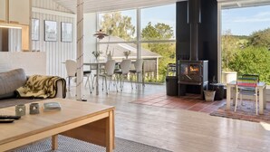 Een moderne woonkamer met een groot raam, een open haard en een eethoek.