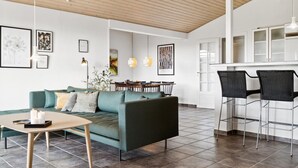 Una sala de estar moderna con un sofá verde, una mesita y un comedor con sillas.