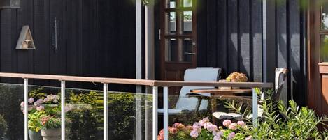 A wooden house with a balcony, potted plants, and a chair.