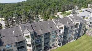 A multi-story hotel with balconies, a parking lot, and a grassy area.