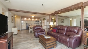 A spacious living room with a leather sofa, a wooden coffee table, and a TV stand.