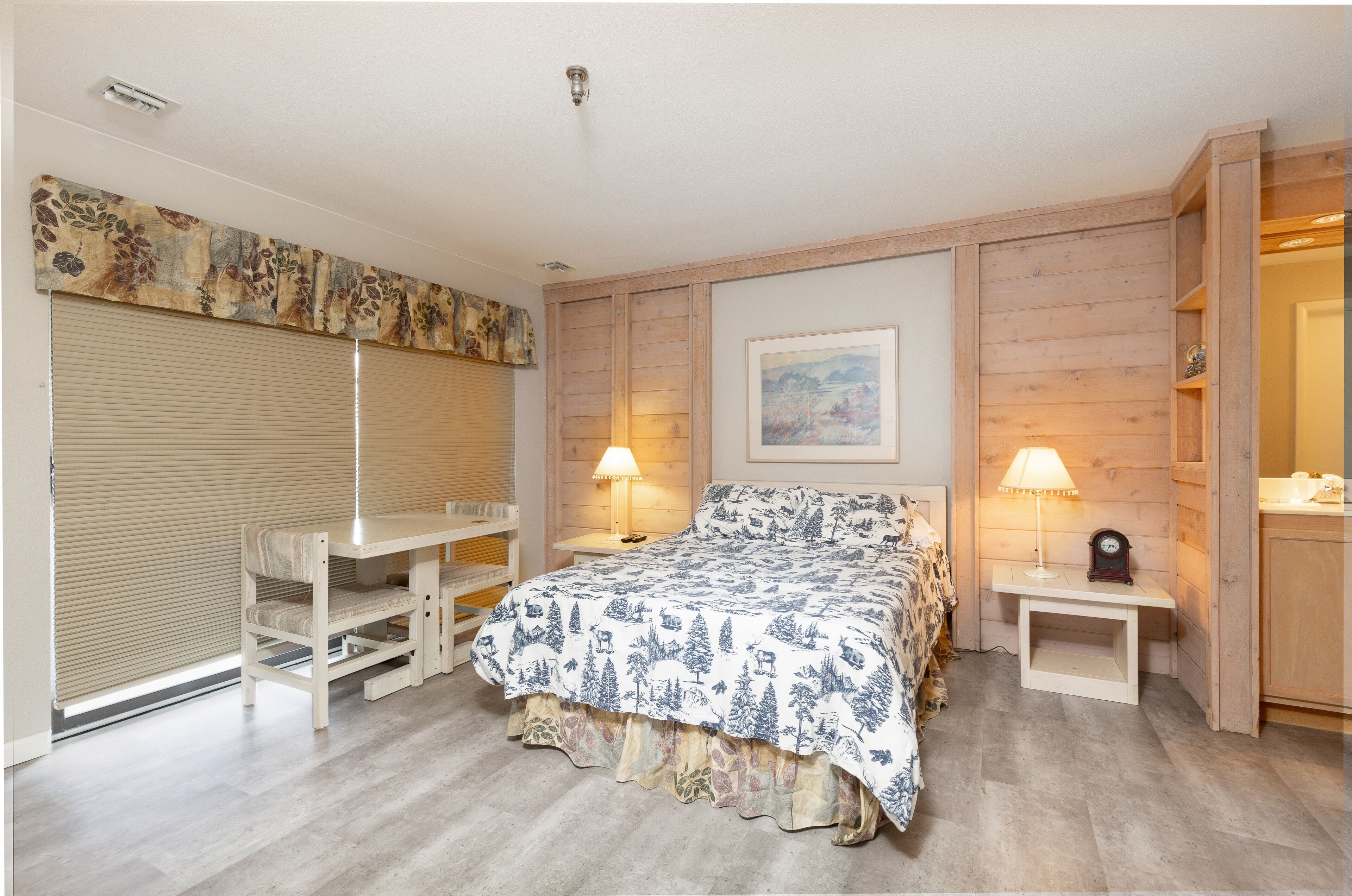 Une chambre à coucher avec un lit, deux tables de chevet, un bureau et une chaise.