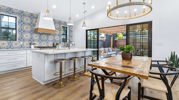 A modern kitchen with a central island, bar stools, pendant lighting, and a chandelier.