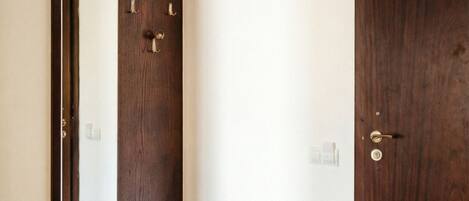Una habitación con un aparador de madera, un espejo grande y una puerta de madera oscura.