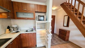 A compact kitchen with wooden cabinets, a microwave, a refrigerator, and a sink.