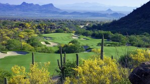 Un parcours de golf offrant une vue sur des montagnes lointaines et une vallée.