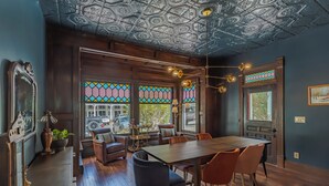 Zona pranzo con tavolo in legno, sedie e soffitto decorato con motivi elaborati.