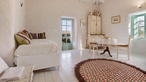 Ein Schlafzimmer mit einem Bett, einem runden Teppich, einem Esstisch mit Stühlen und einem Schrank.
