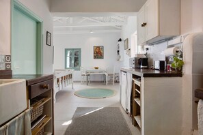 A kitchen with a dining area, white cabinets, a microwave, and a refrigerator.