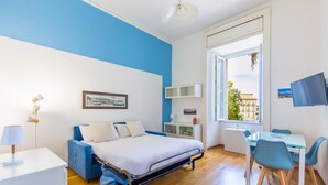 Ein modernes Schlafzimmer mit Bett, Nachttisch, Lampe und Schreibtisch mit Stühlen.