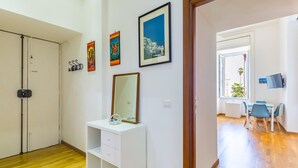 Ein Zimmer mit einem weißen Schminktisch, einem Spiegel und Bildern an der Wand. Ein Holzboden und eine Tür zu einem anderen Raum sind ebenfalls vorhanden.