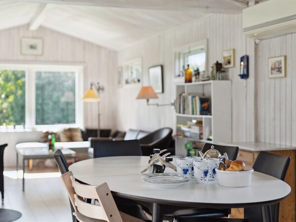 A dining area with a round table, chairs, and a buffet with dishes and utensils.