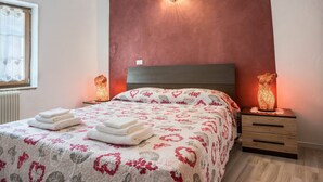 Een slaapkamer met een bed, twee bedlampen, een raam en een radiator.
