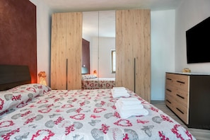 Una camera da letto con un letto, un armadio in legno e una televisione.