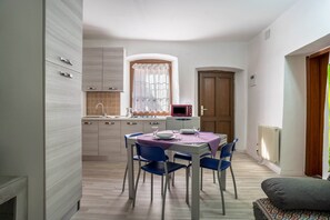 Un'area pranzo con tavolo apparecchiato per quattro persone, un forno a microonde e una finestra con tende.