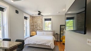 A modern bedroom with a bed, a desk, and a TV. - Downtown+HotTub+Wifi+FreeParking @ 151 Spring Suite E (Eureka Springs)