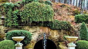 A stone tunnel entrance with a decorative gate, surrounded by well-maintained hedges and a stone wall. - Downtown+HotTub+Wifi+FreeParking @ 151 Spring Suite E (Eureka Springs)