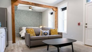 A modern living room with a grey sofa, a round coffee table, and a stone accent wall. - Downtown+HotTub+Wifi+FreeParking @151 Spring Ste A (Eureka Springs)