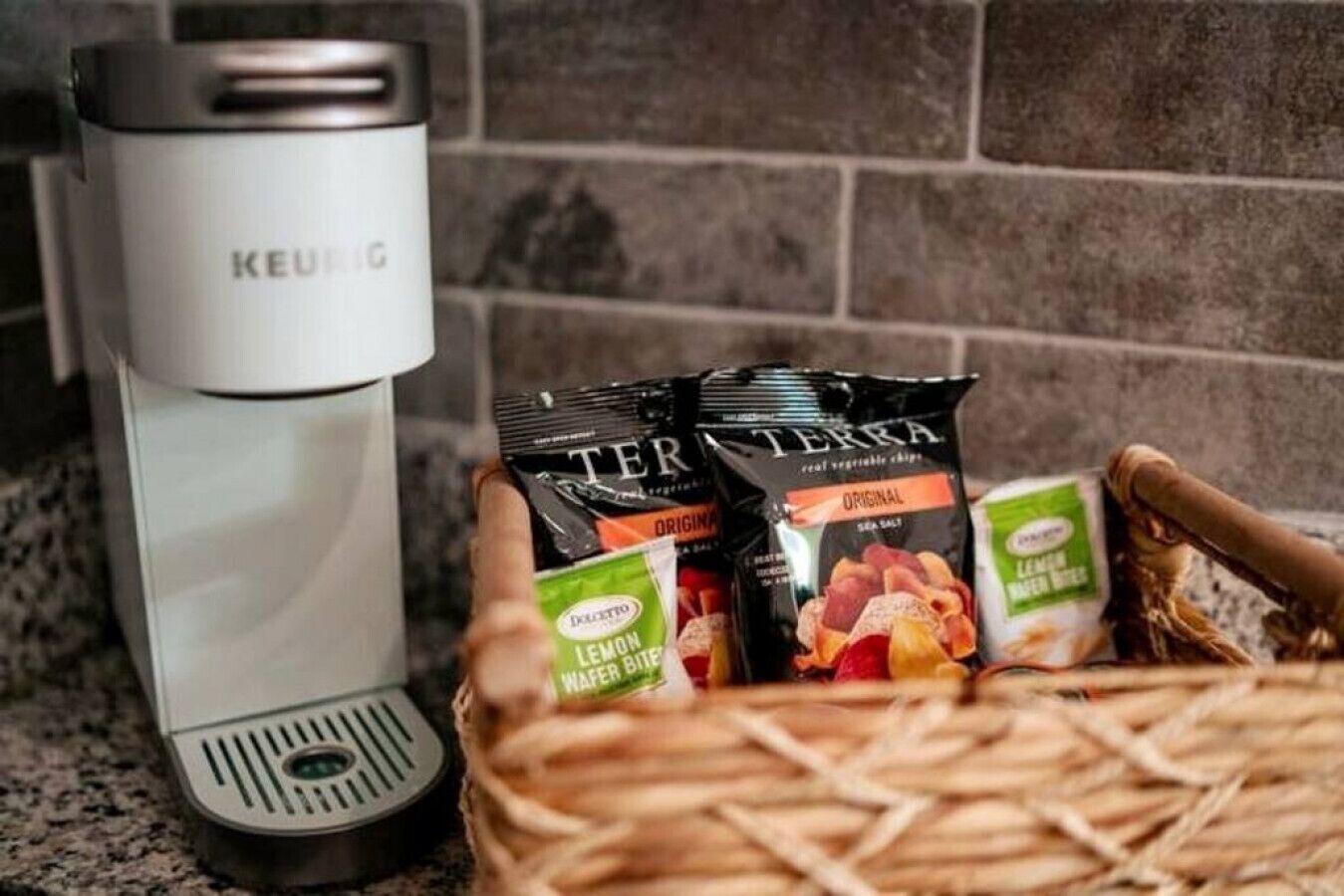 Une machine à café Keurig et un panier contenant du sel de mer Terra Terra et des biscuits au citron.