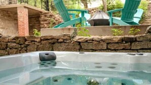 A hot tub with a stone wall and green chairs in the background. - Downtown+HotTub+Wifi+FreeParking @151 Spring Ste C (Eureka Springs)