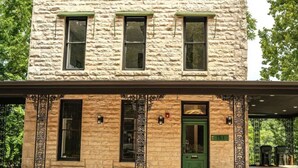 A two-story stone building with a green door and black-framed windows. - Downtown+HotTub+Wifi+FreeParking @151 Spring Ste C (Eureka Springs)