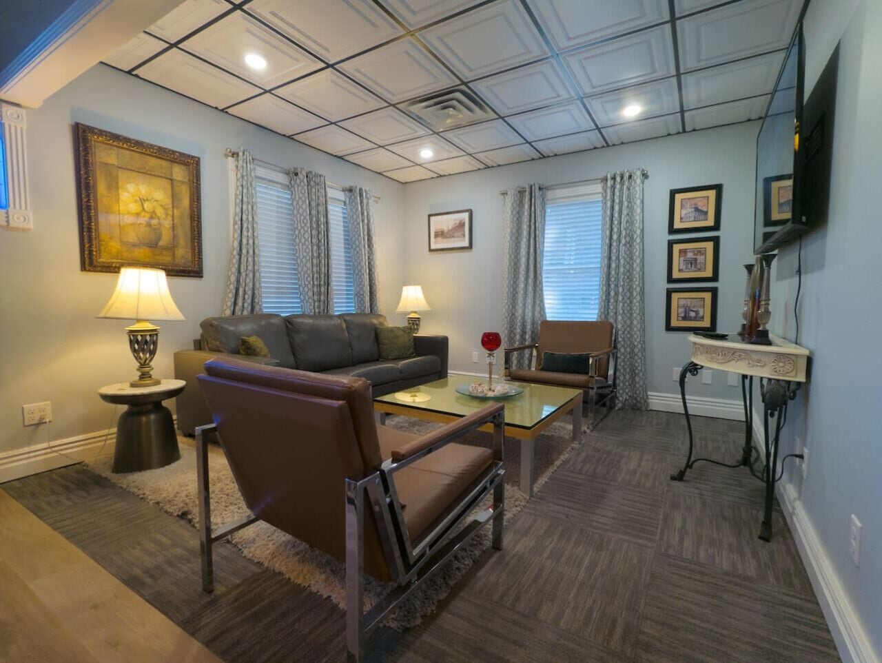 A living room with a sofa, armchair, coffee table, and a TV on a stand.
