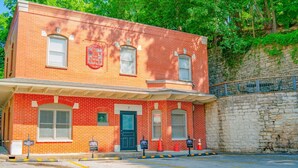 A red brick building with a green door, numbered 7, and a small porch area. - Downtown Villa 2 at Sweet Spring Wifi Free Parking (Eureka Springs)
