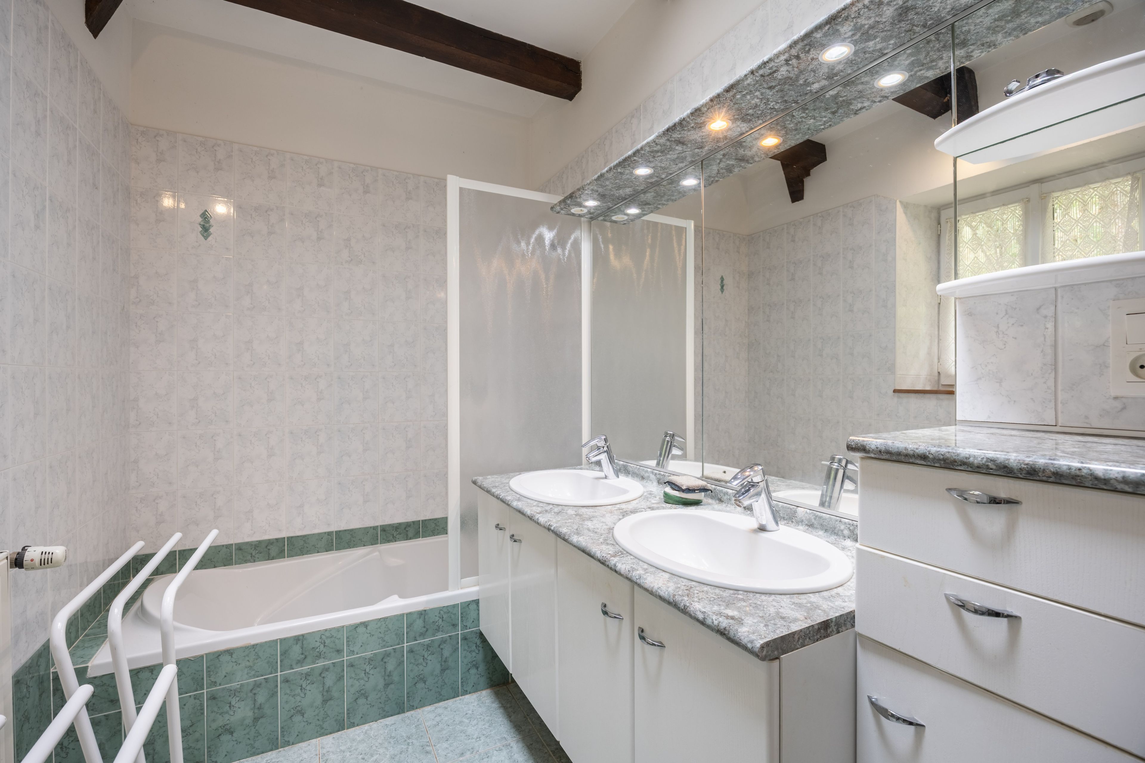Un bagno moderno con due lavabi, una vasca e uno specchio grande.
