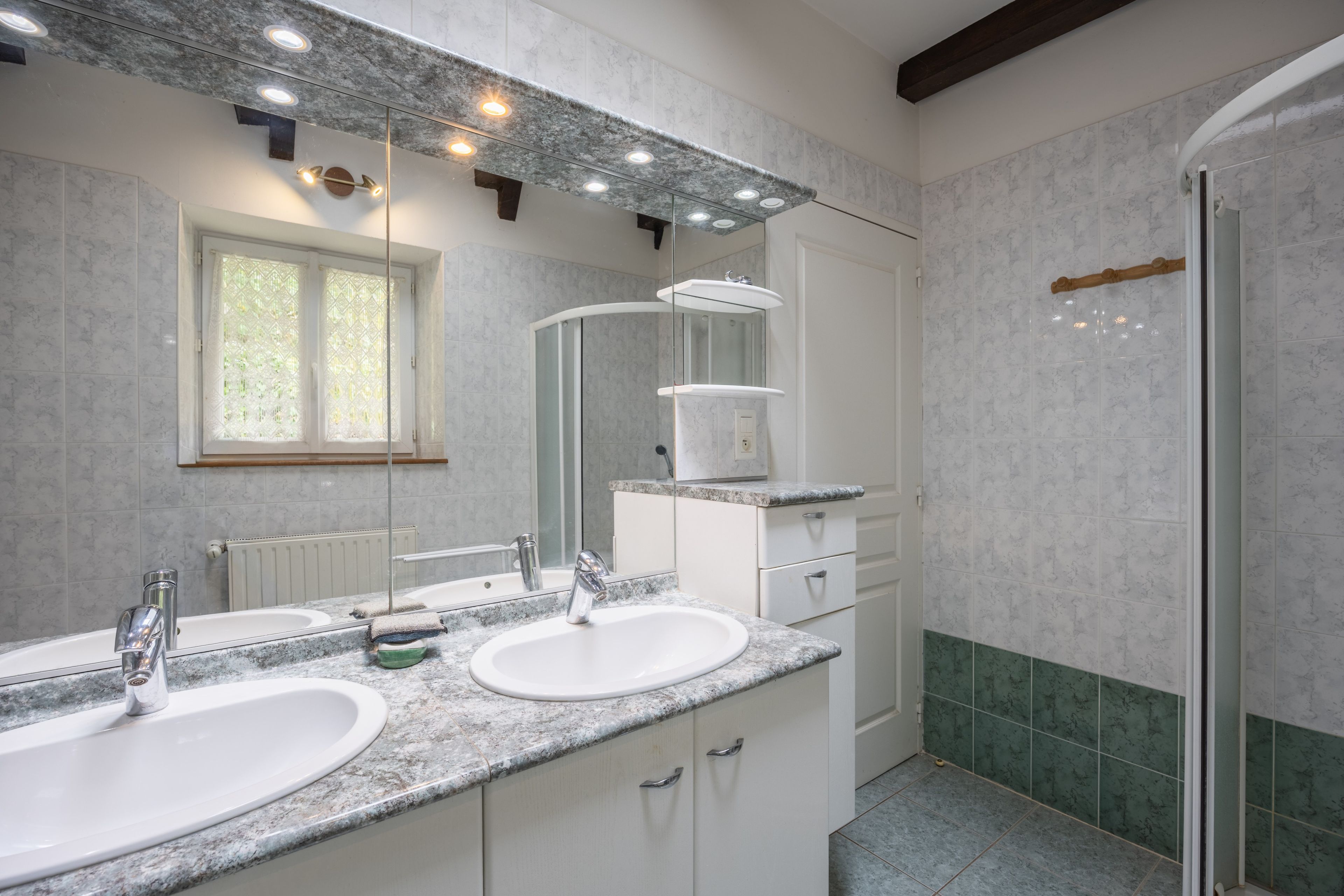 Une salle de bain avec deux lavabos, un miroir et une douche.