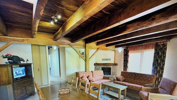 A spacious living area with a wooden dining table, sofas, and a fireplace.