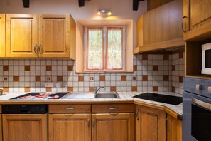 Une cuisine avec des meubles de rangement en bois, un pare-feu en carrelage, une fenêtre avec des rideaux et un four à micro-ondes.