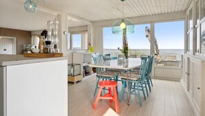 A spacious dining area with a large table and chairs, a kitchen area with a wooden countertop, and large windows offering a view of the sea. - "Alimpij" - 5m from the sea by Interhome (Børkop)