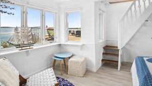 A room with a wooden staircase, a small round table, a white pouf, and a bed with a patterned bedspread. - "Alimpij" - 5m from the sea by Interhome (Børkop)