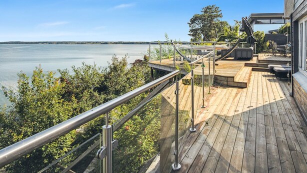 A wooden deck with a metal railing overlooking a body of water, with a clear sky above. - "Alimpij" - 5m from the sea by Interhome (Børkop)