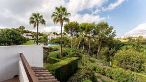A landscaped garden with a pool, palm trees, and a white building.