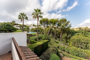 Un jardin aménagé avec une piscine, des palmiers et un bâtiment blanc.